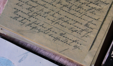 A hand-written manuscript open on a studio desk