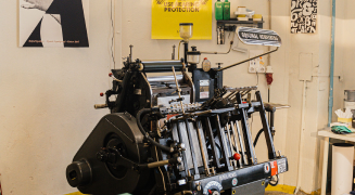 A letterpress workshop with a proof pinned above the bed