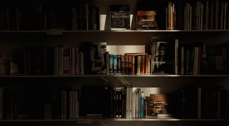 A dark library shelf of bound reference volumes