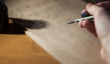 A dip pen drawing a line across a sheet of heavy paper