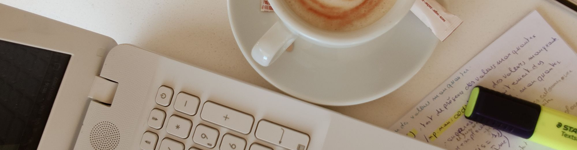 A keyboard, a cup of coffee and an annotated page on a desk